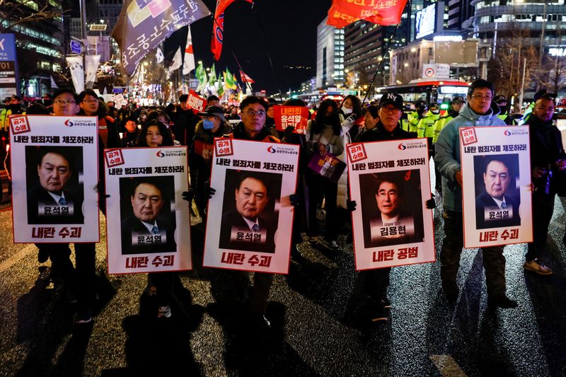 © Reuters. Protesters hold placards during a candlelight vigil to condemn South Korean President Yoon Suk Yeol's surprise declarations of the failed martial law and to call for his resignation in Seoul, South Korea, December 5, 2024. REUTERS/Kim Kyung-Hoon