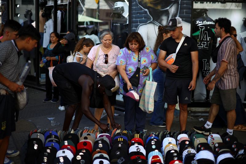 © Reuters. FILE PHOTO: People shop before Christmas at a street market, as Argentina is trying to improve its battered economy, but tough austerity measures by libertarian President Javier Milei, which have helped lower inflation and stabilize state finances, have also taken a toll on many sectors of the economy, in Buenos Aires, Argentina December 23, 2024. REUTERS/Agustin Marcarian/File photo