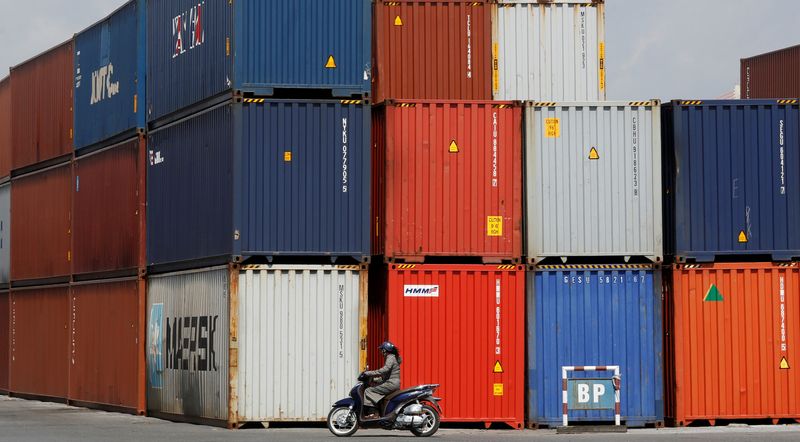 © Reuters. FILE PHOTO: A woman rides a motorcycle as she passes containers at Hai Phong port, Vietnam September 25, 2018. Picture taken September 25, 2018. REUTERS/Kham/File Photo